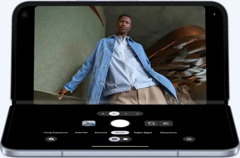 Pixel 10 Pro Fold in tabletop mode taking a photo of a person. The top screen displays the photo, the bottom screen displays the camera controls