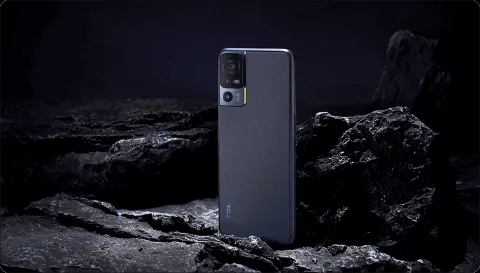 TCL 40 SE in Dark Grey, back view on a dark rock background