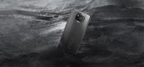 POCO X3 NFC in Shadow Gray, back view resting on dark sand